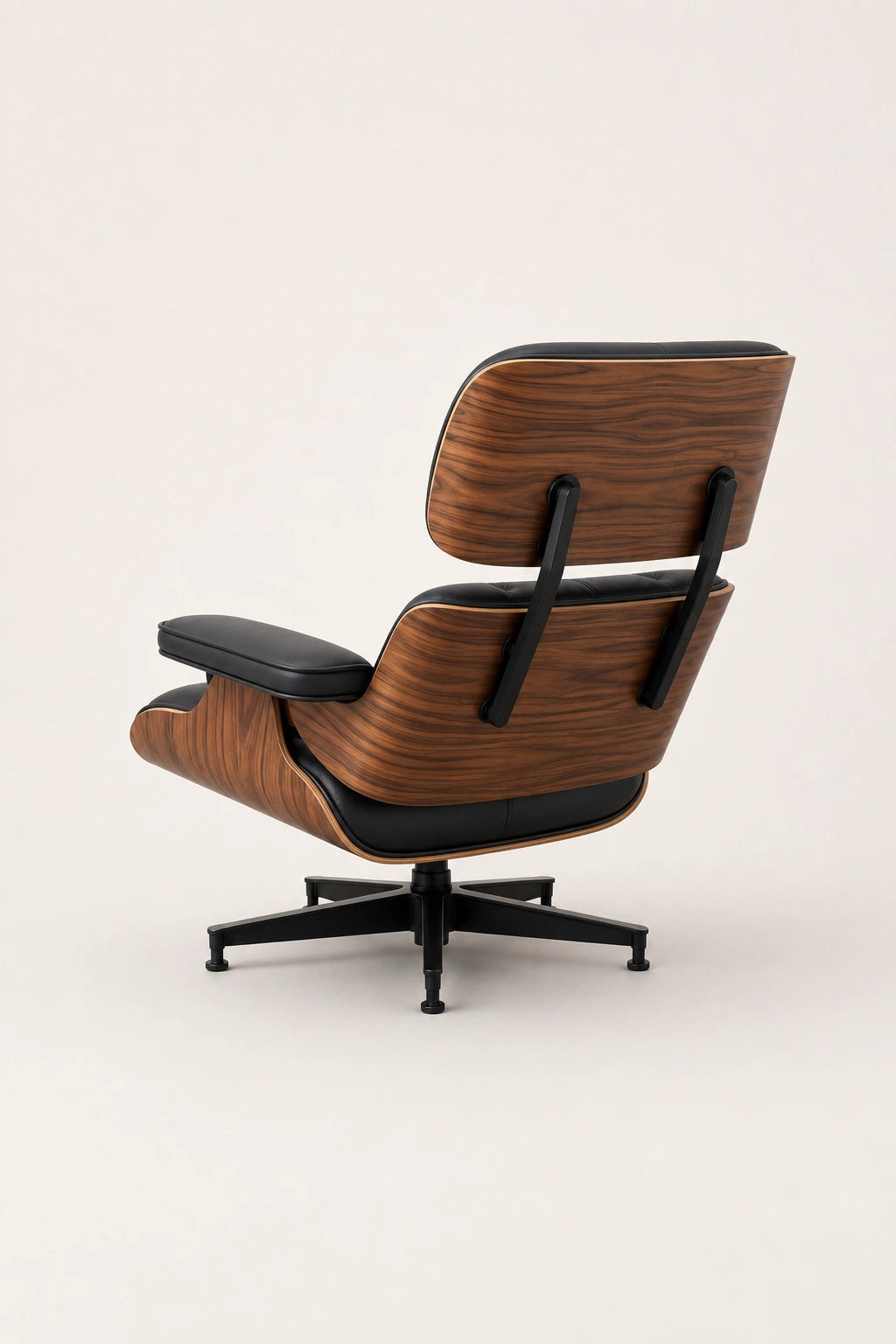 Rear three-quarter view of executive lounge chair showing the curved walnut shell and black metal supports