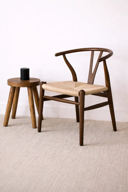 Front view of mid-century wooden wishbone chair UK featuring curved walnut frame and hand-woven rattan seat.