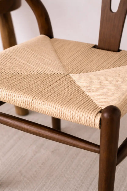Close-up of woven rattan seat on mid-century wooden wishbone chair with walnut frame craftsmanship detail.