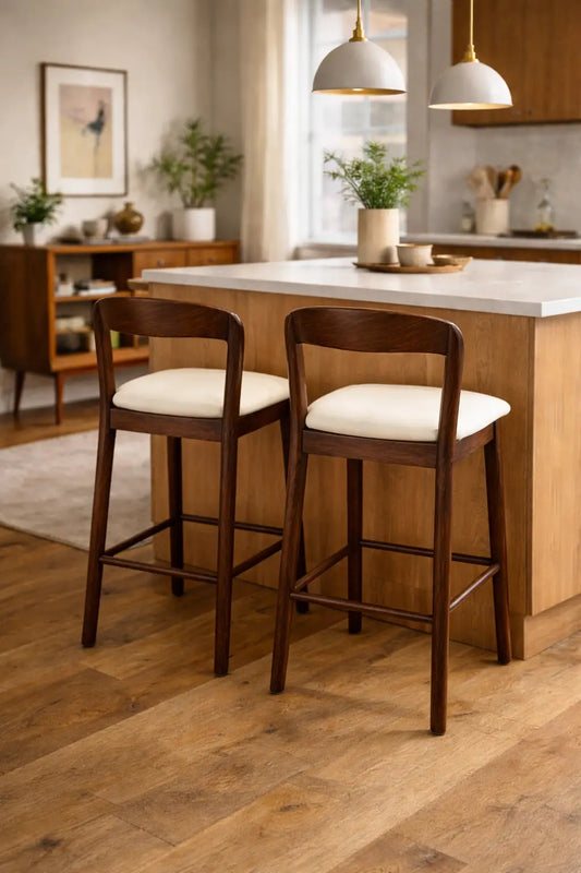 Two wooden bar stools with white cushions in a kitchen setting.