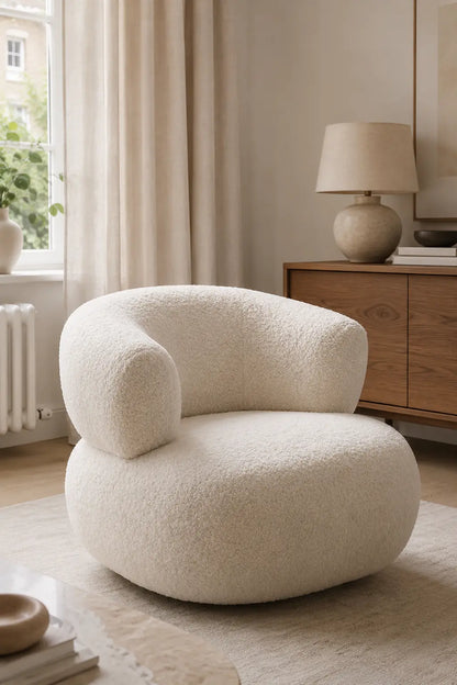 Modern white bouclé armchair in a warm living room with sideboard and soft curtains