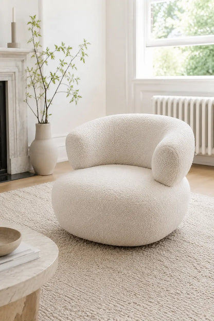 White bouclé living room armchair styled beside a fireplace in a modern UK home