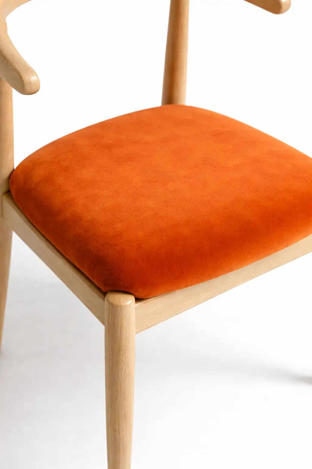 Contemporary oak dining chair with curved wooden backrest and burnt orange velvet upholstered seat.