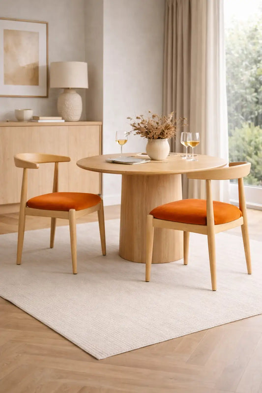 Scandinavian oak dining chairs with burnt orange velvet seats styled around a round wooden dining table in a modern UK dining room.
