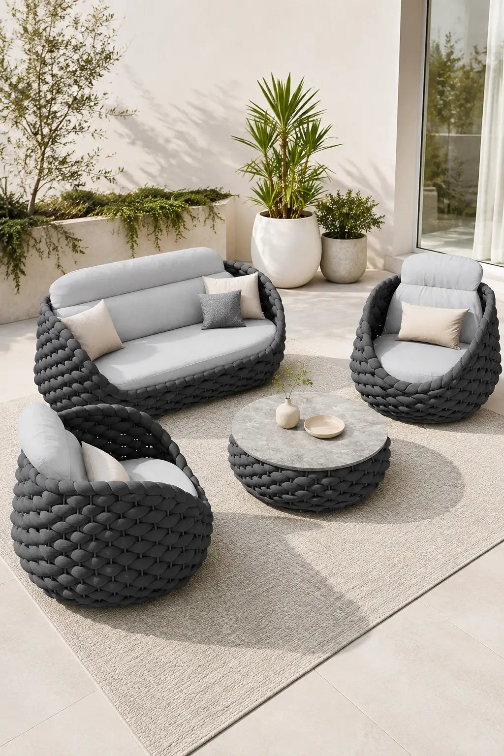 Outdoor patio set with wicker chairs and table on a patio with plants in the background
