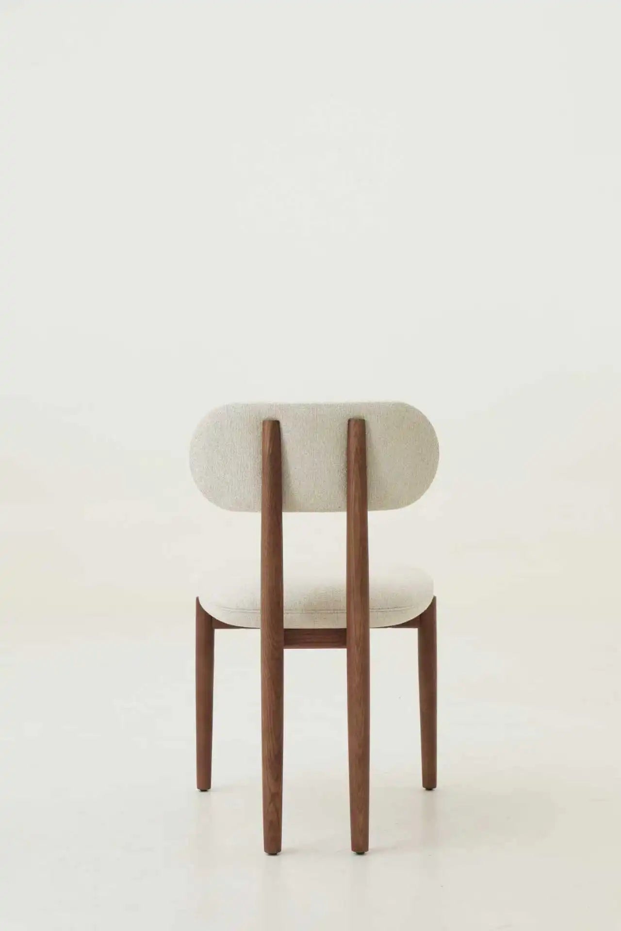 Minimalist chair with wooden legs and a white cushioned seat on a light background