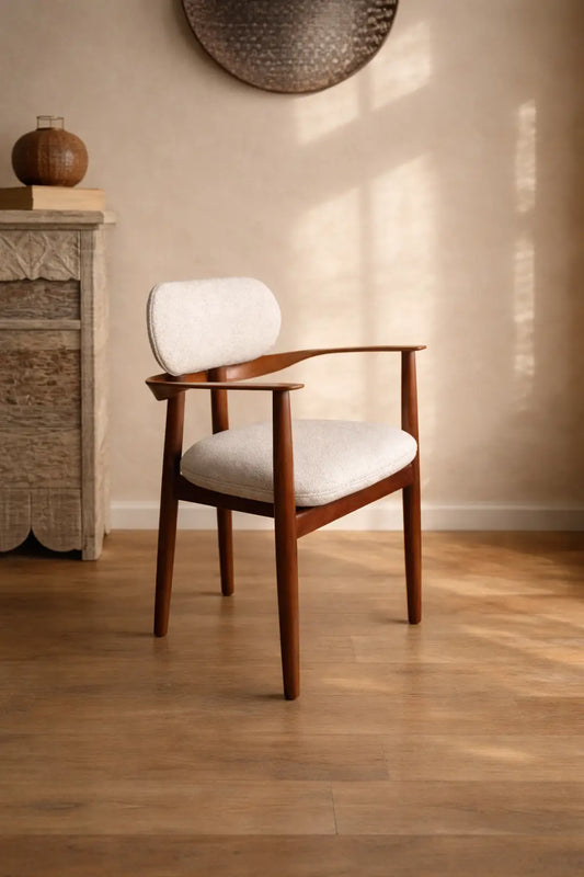 Wooden chair with white cushion on a wooden floor in a room with a neutral wall.