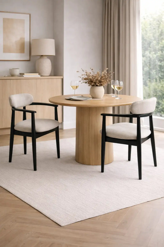 Dining room with a round wooden table and four chairs in a well-lit room.