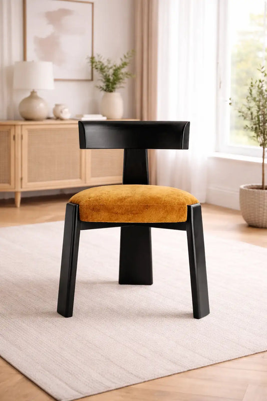 mid century upholstered dining chair UK with black wooden frame and mustard fabric seat in minimalist UK home interior