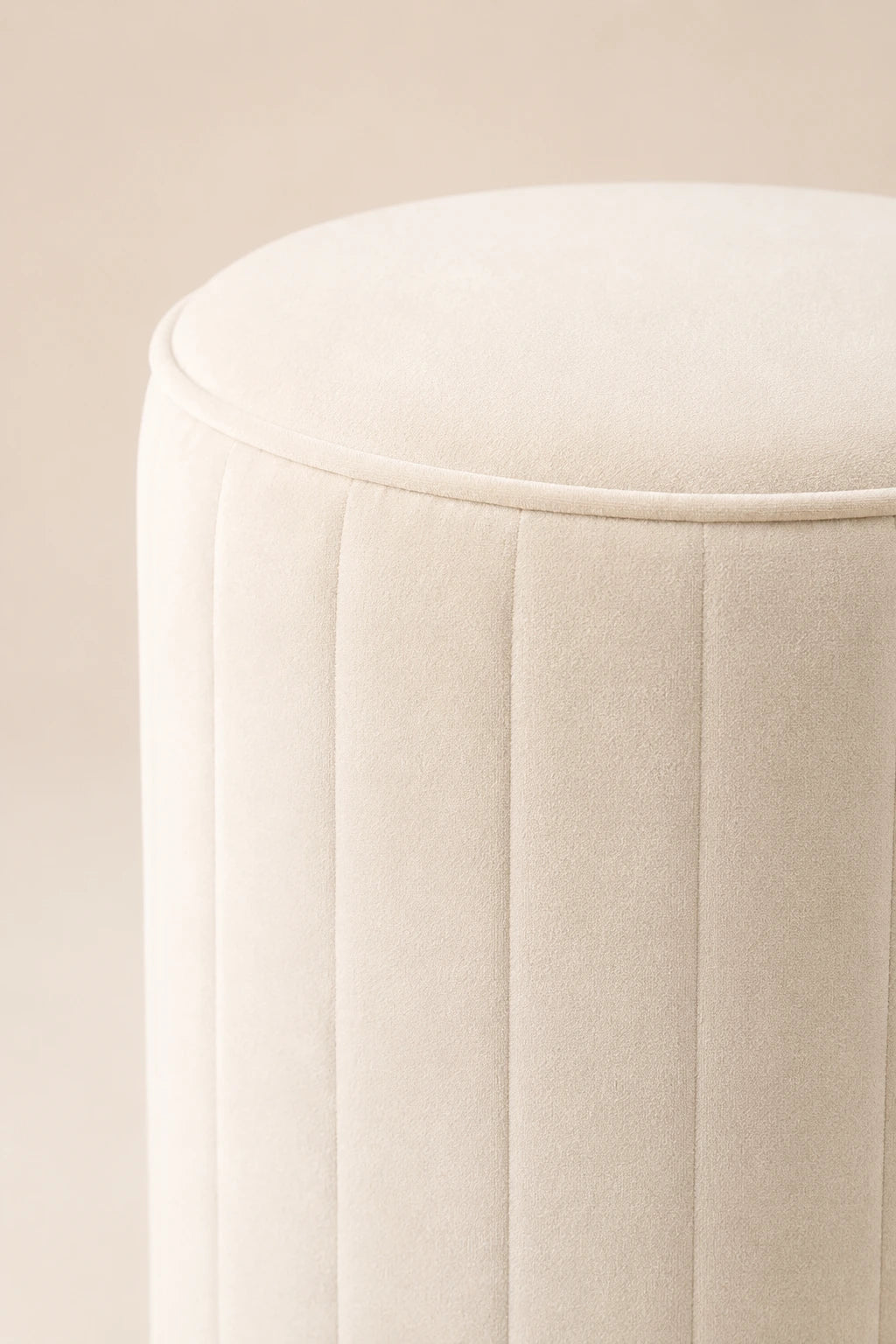 Close-up of a beige cushioned stool on a beige background