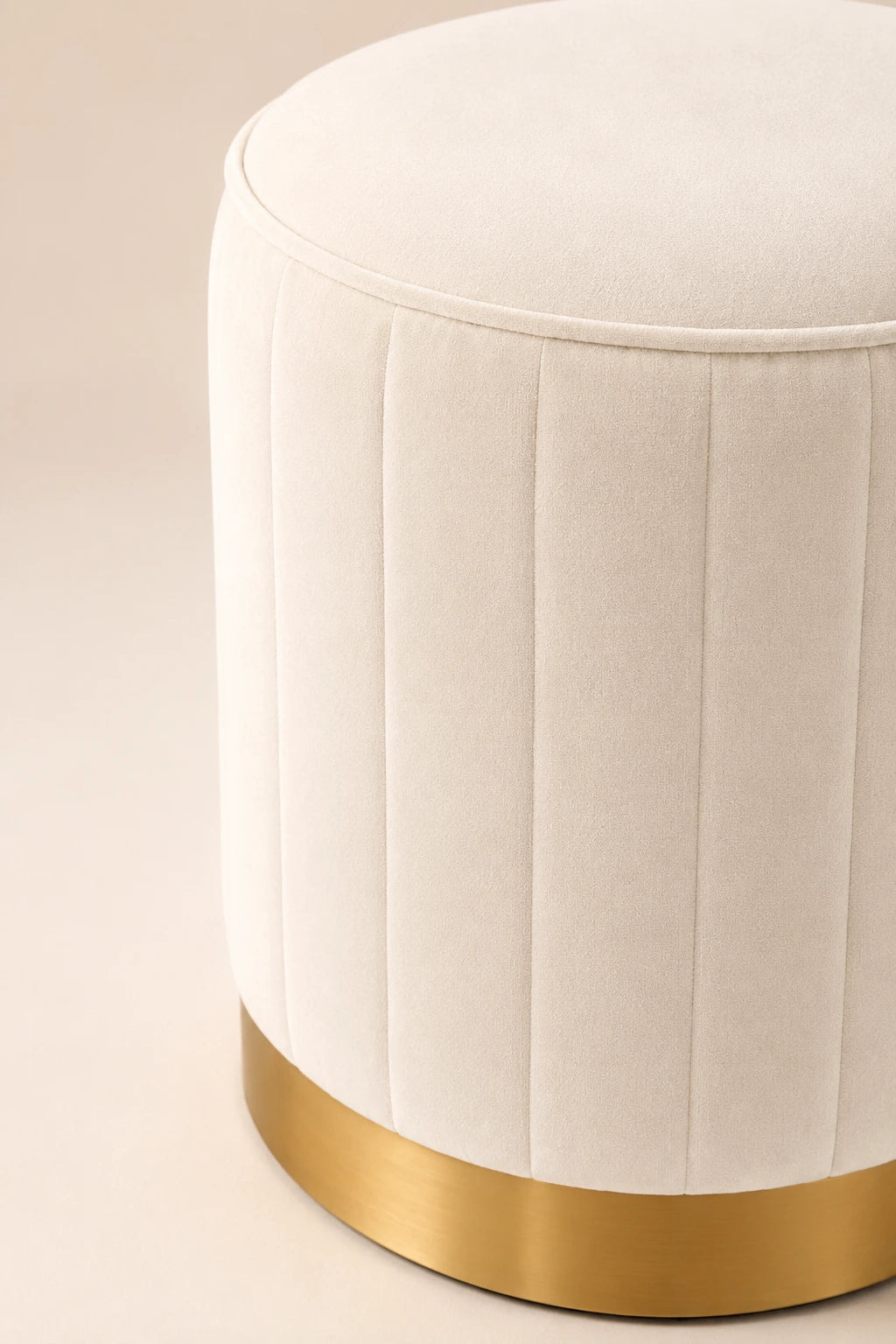 White ottoman with a gold base on a beige background