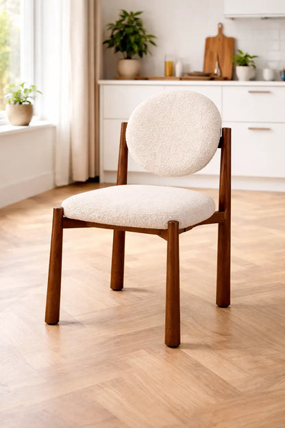 mid century modern boucle dining chair UK styled in bright kitchen interior with wooden flooring and natural light