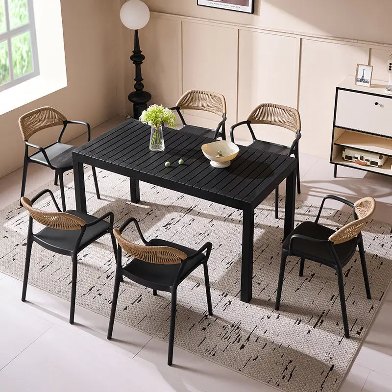 Black dining table with wicker chairs in a room with a lamp and window.