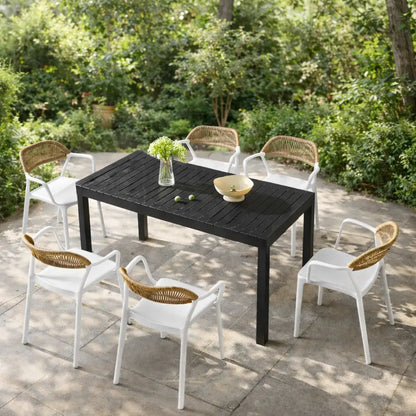 Outdoor dining set with a black table and white chairs with wicker backs on a patio.