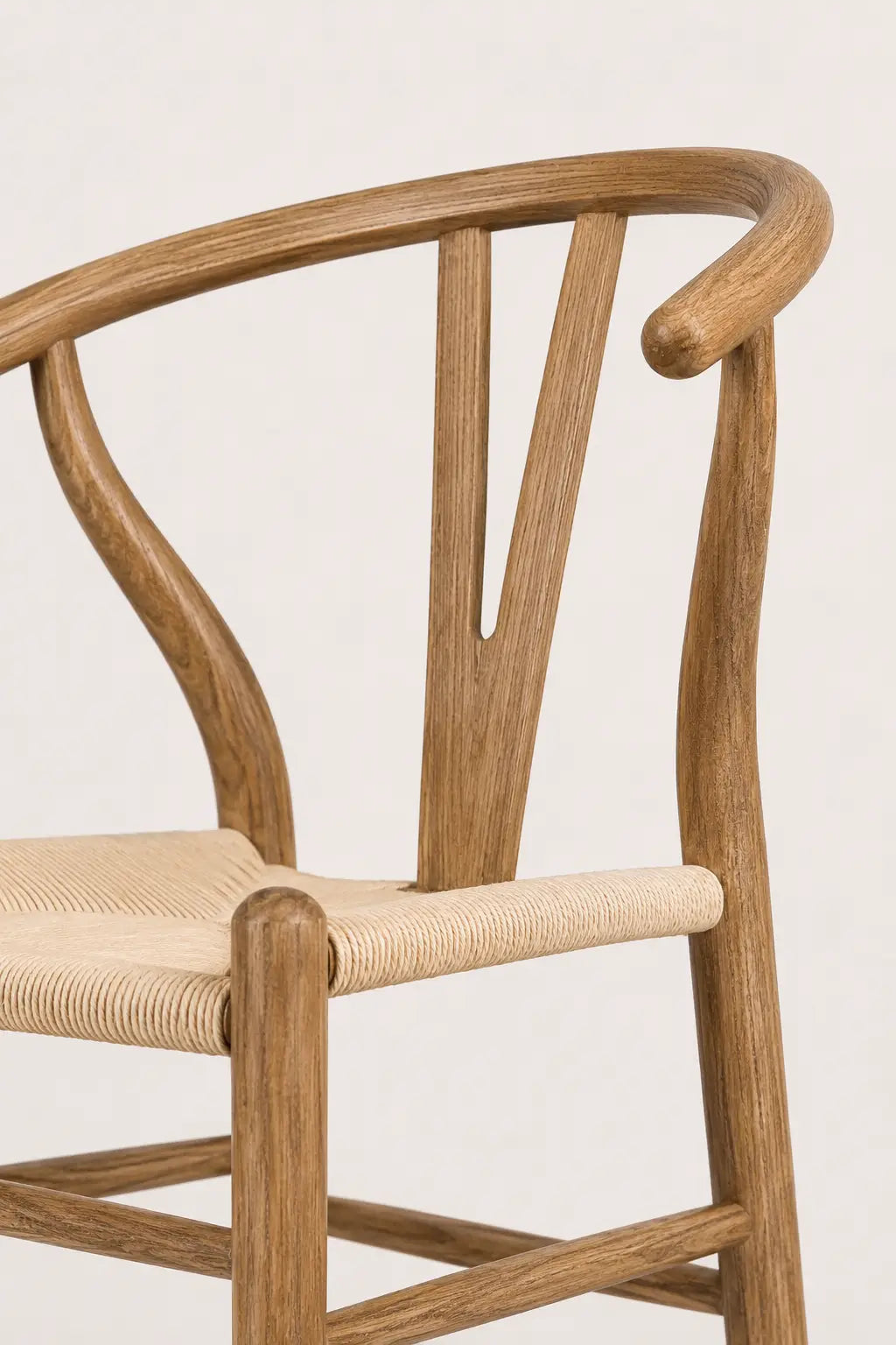 Close-up of the Birk dining chair’s woven rattan seat and walnut-colour ash wood frame
