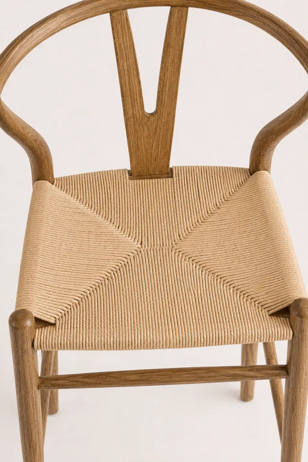Front view of Birk wishbone dining chair with curved ash wood frame, walnut-colour finish and woven rattan seat