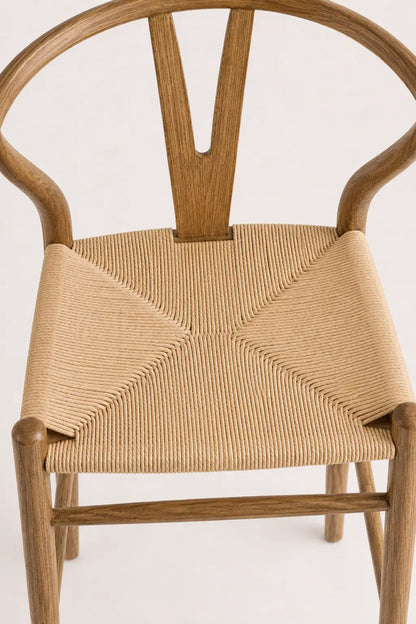 Front view of Birk wishbone dining chair with curved ash wood frame, walnut-colour finish and woven rattan seat