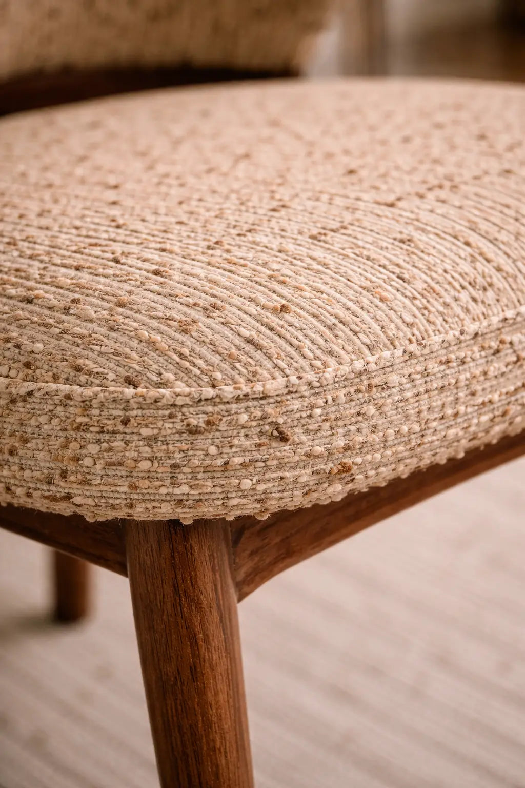 Close-up of a textured chair seat with wooden legs on a blurred background