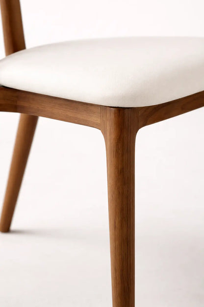 Wooden chair with white cushion on a light background