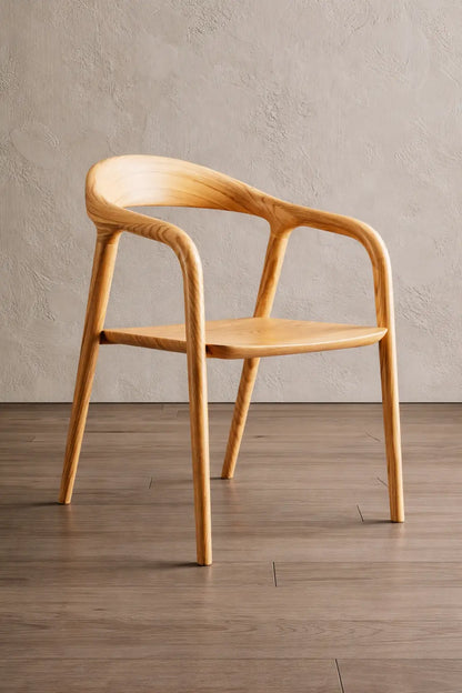 Wooden chair with curved armrests on a wooden floor against a beige wall