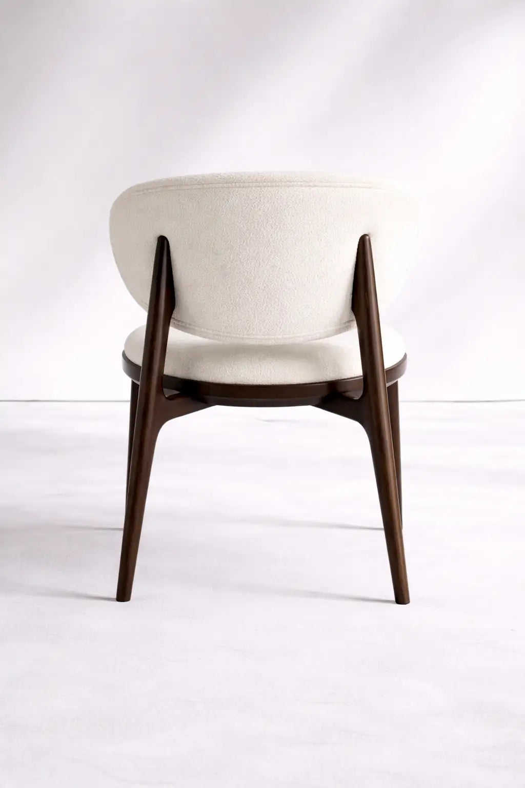 Back view of UK mid-century wooden chair with curved cream boucle backrest and solid walnut frame.