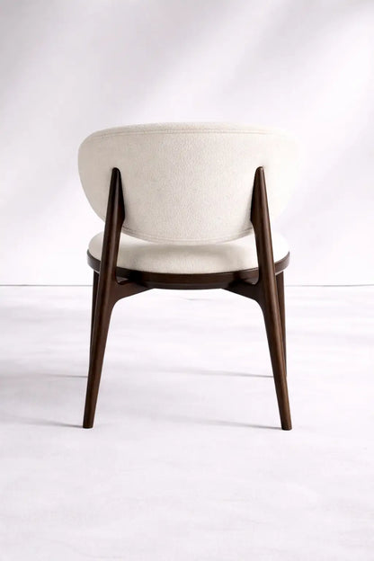 Back view of UK mid-century wooden chair with curved cream boucle backrest and solid walnut frame.
