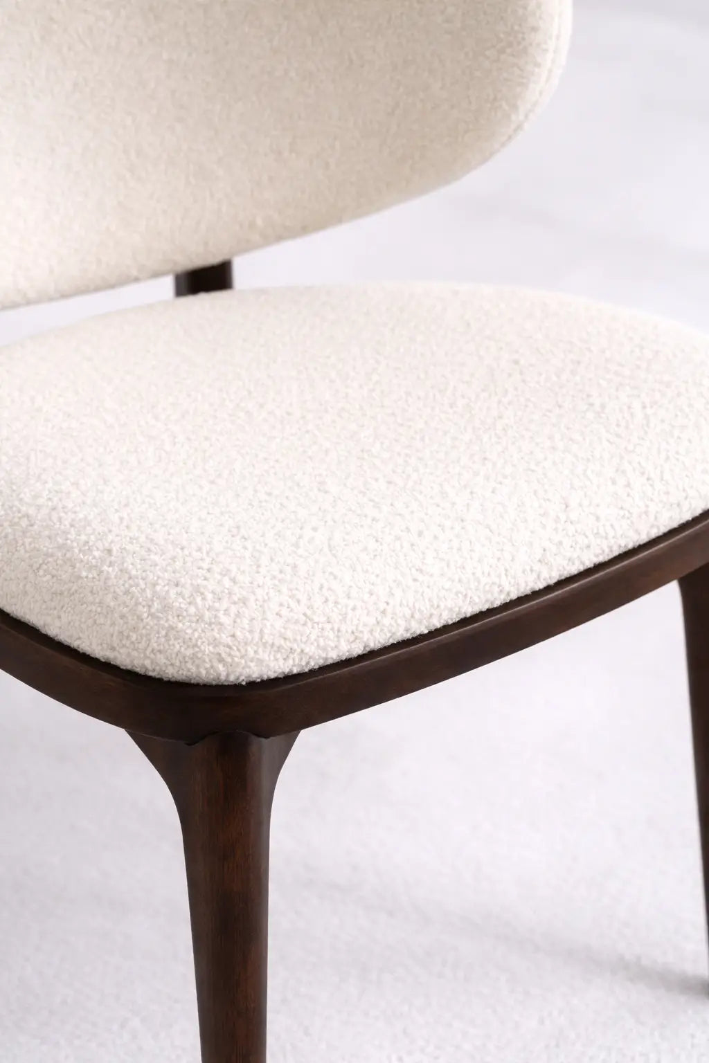 Close-up of cream boucle seat cushion on UK mid-century wooden chair with dark walnut frame.