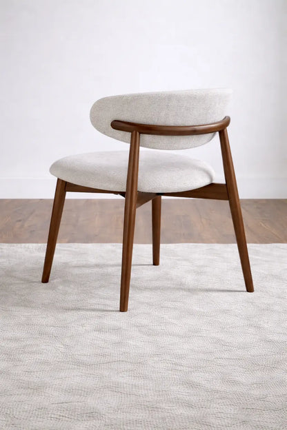 Mid century modern walnut dining chair shown at 45 degree angle with cream fabric seat, premium UK dining furniture.
