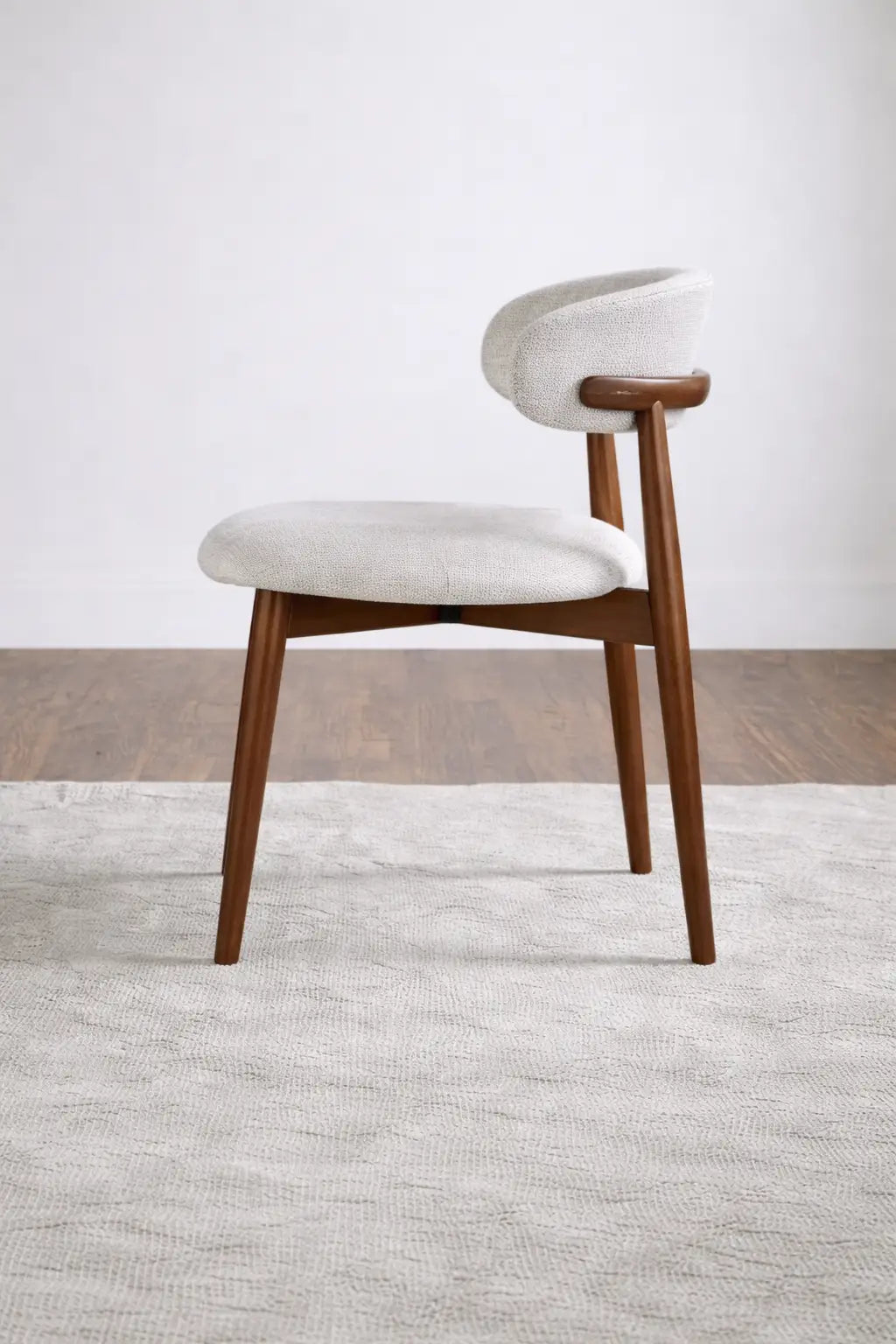 Side profile of walnut dining chair with curved upholstered back and tapered legs, ideal for modern UK dining spaces.
