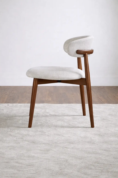 Side profile of walnut dining chair with curved upholstered back and tapered legs, ideal for modern UK dining spaces.