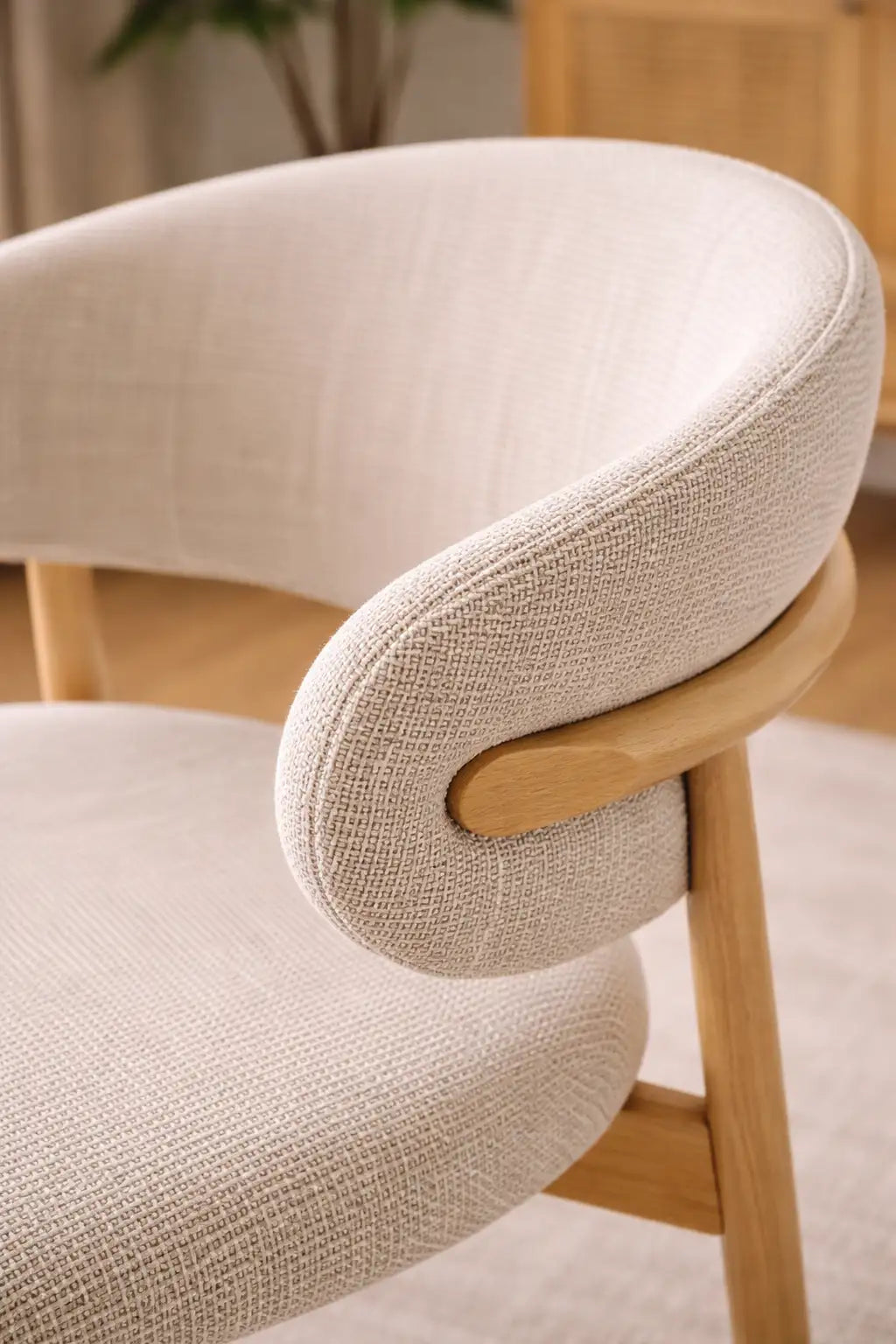 Close-up of a beige upholstered chair with wooden armrests and legs.