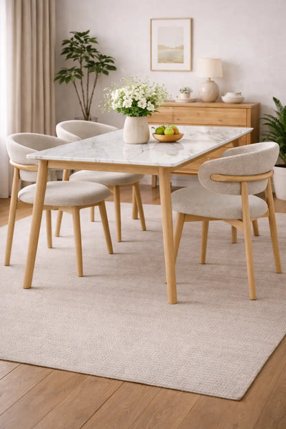 Dining room with a marble table and wooden chairs on a light rug.