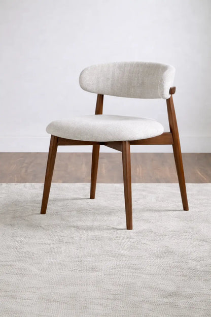 Chair with wooden legs and white cushioned seat and backrest on a neutral background