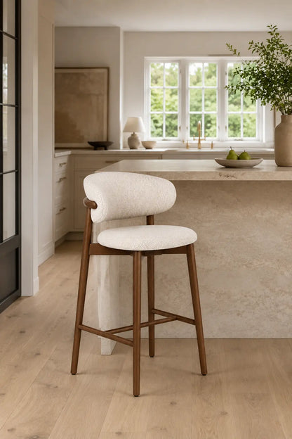 Side view of cream upholstered bar stool for kitchen island with wooden legs and curved back support
