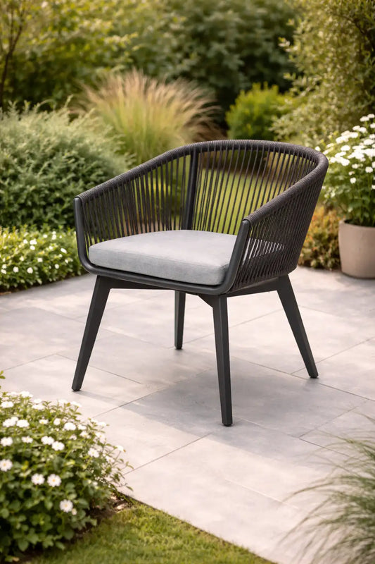 Black outdoor rope dining chair with cushion in a landscaped garden setting