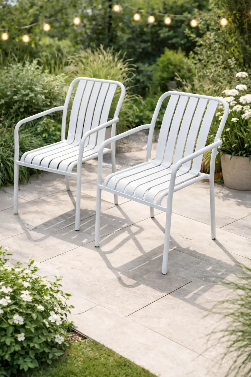 Two white metal outdoor dining chairs in a modern UK garden patio setting