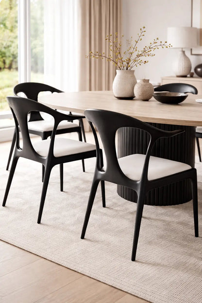 Close-up of modern black dining chairs styled in neutral UK dining room with light wood table and soft natural lighting.