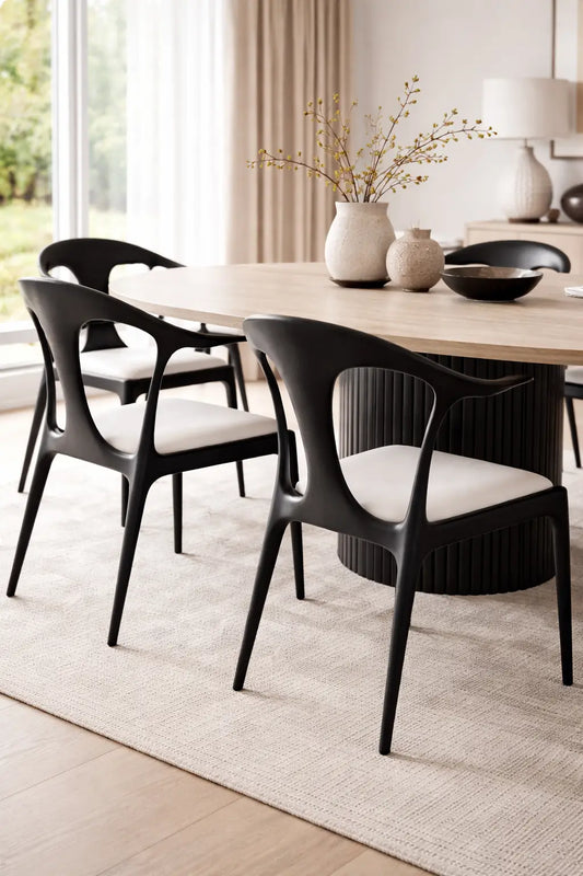 Close-up of modern black dining chairs styled in neutral UK dining room with light wood table and soft natural lighting.