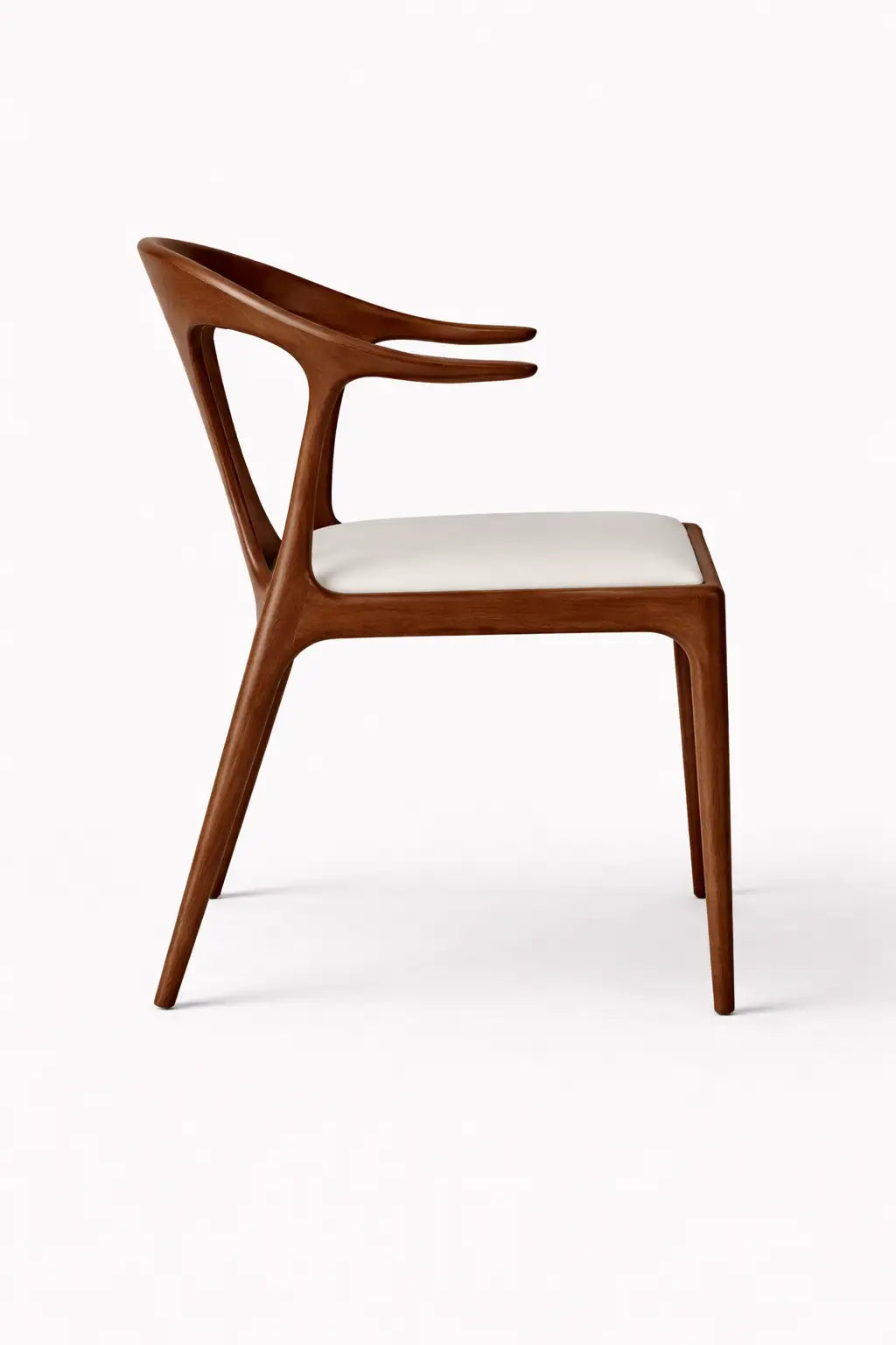 Close-up of sculptural solid walnut dining chair with curved backrest and arm detail in modern UK dining space.