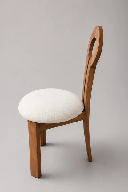 Mid-century key dining chair with upholstered seat, light walnut wood frame and keyhole backrest, angled side view