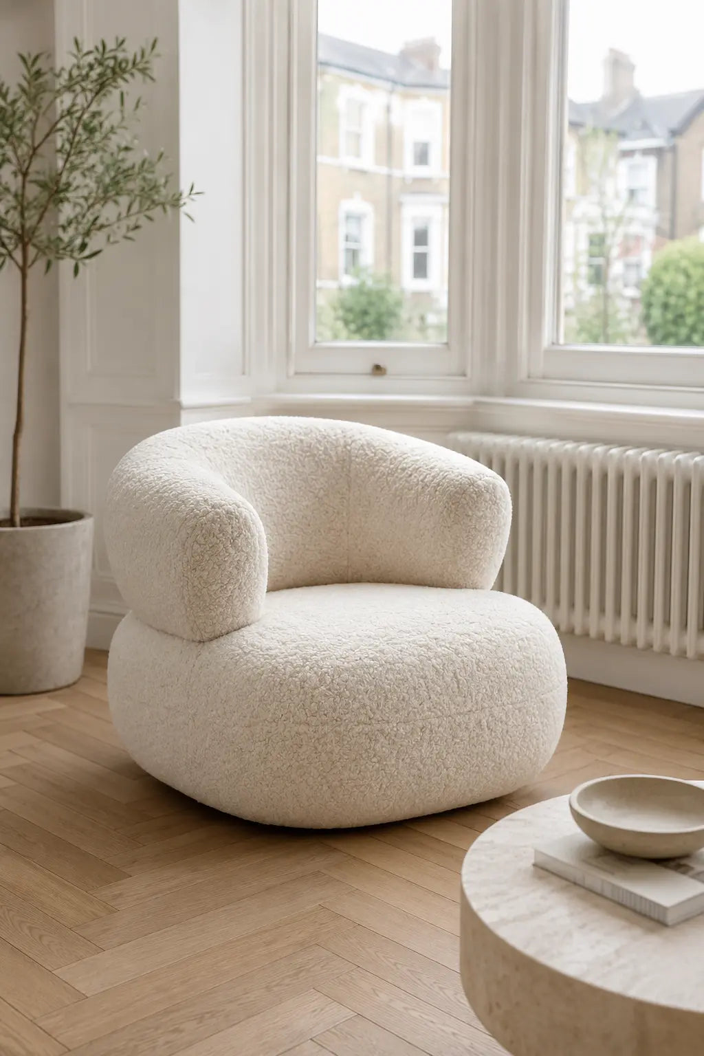 White bouclé living room armchair in a bright modern interior by the window