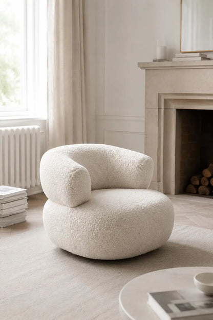 Modern white bouclé armchair in a warm living room with sideboard and soft curtains