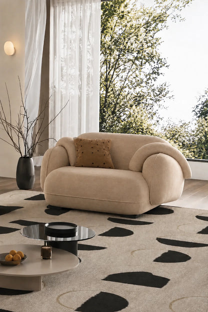 Beige velvet armchair side view with sculptural rolled arms and low profile base