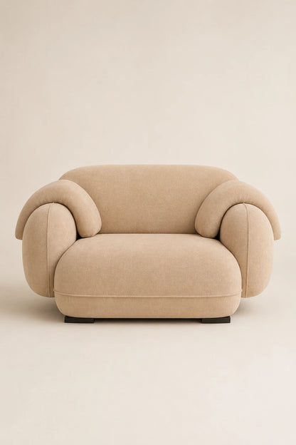 Beige velvet armchair front view with sculptural curved arms and deep seat