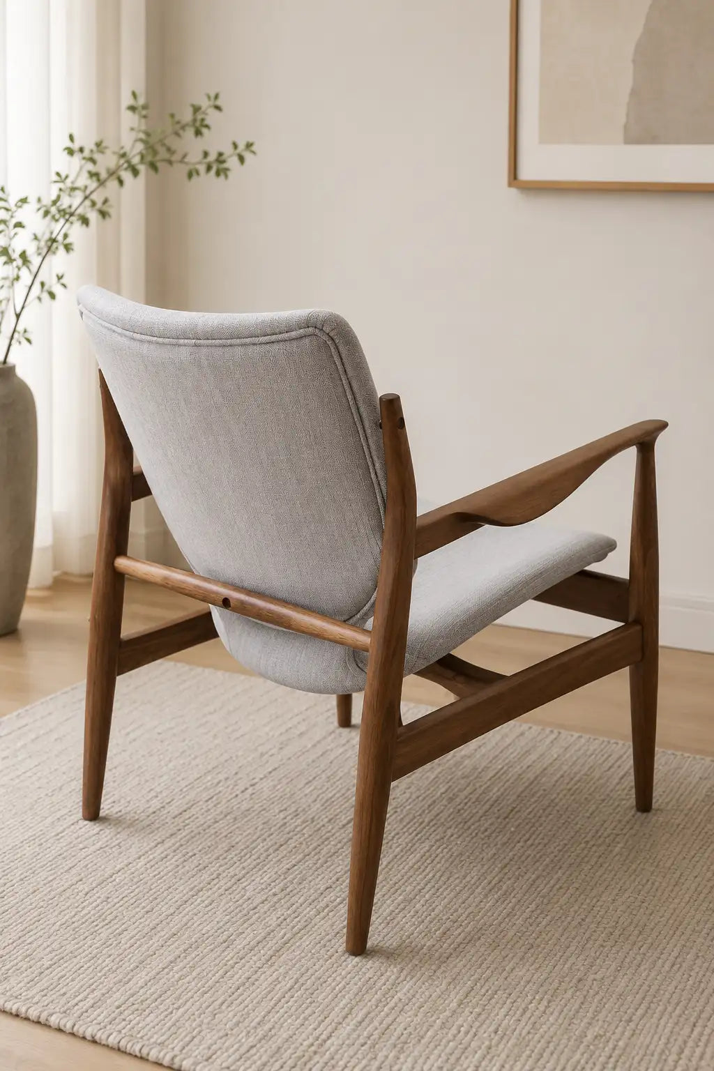Side view of a walnut wood upholstered lounge chair with curved arms and mid-century silhouette